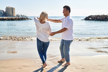 Middle age man and woman couple smiling confident dancing at seaside