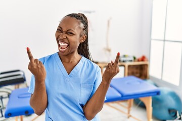 Black woman with braids working at pain recovery clinic showing middle finger doing fuck you bad...