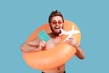 Portrait of excited bearded man standing with orange rubber ring, holding passport document,...