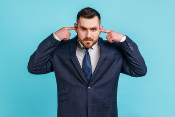 I don't want to here this. Portrait of businessman wearing official style suit standing and holding...