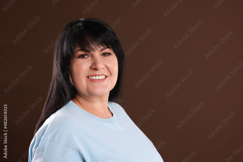 Canvas Prints Beautiful overweight mature woman with charming smile on brown background. Space for text