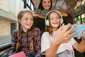 Girls laughing and using cellphone while going on school bus