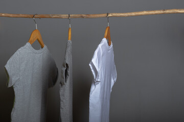 Cotton clothes in natural colors hang on a wooden hanger on a gray background