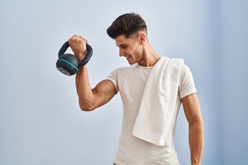 Young hispanic man smiling confident training using kettlebell at sport center