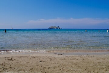 Fototapeta na wymiar Sandy Barcaggio beach with clear turquoise water and view of Ile de la Giraglia. Corsica, France.