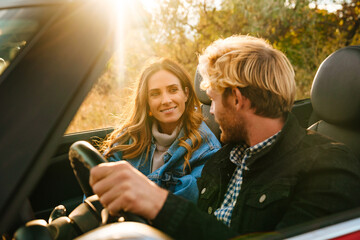 White couple smiling together while driving in car during trip