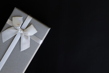 Brown gift box with luxury bow on dark background with copy space,