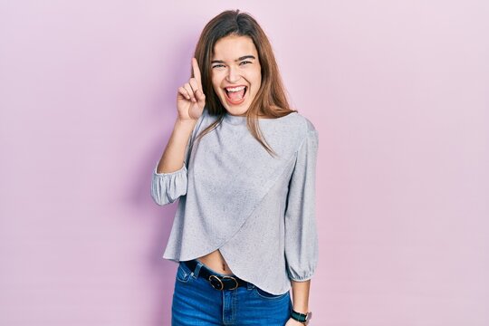 Young caucasian girl wearing casual clothes pointing finger up with successful idea. exited and happy. number one.