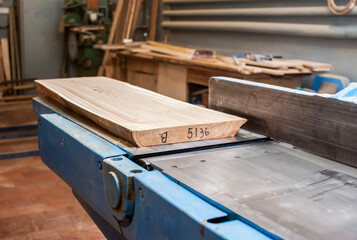 The board lies on a metal machine in a carpentry workshop