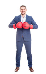 Full length businessman in suit with boxing gloves stands ready in a fighting stance, punching his...