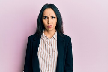 Young hispanic girl wearing business clothes skeptic and nervous, frowning upset because of...