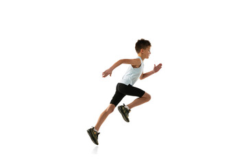 Side view portrait of little boy in motion, running isolated over white studio background