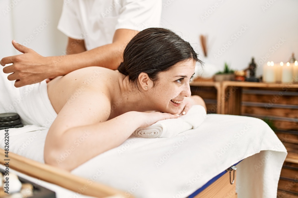 Poster woman smiling happy reciving back massage at the clinic.