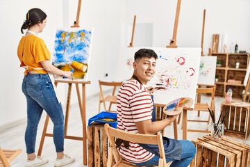 Obraz premium Two hispanic paint students smiling happy painting at art studio.