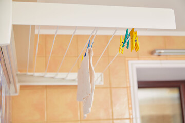 Different colored plastic clothespins hang on dryer