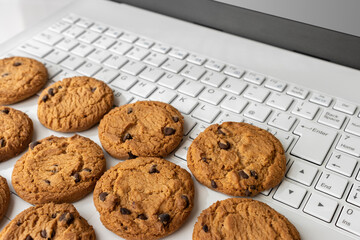 ノートパソコンのキーボードとクッキー。デジタルデバイスのCookieイメージ