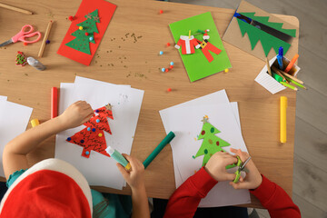 Little children making beautiful Christmas greeting cards at table, top view