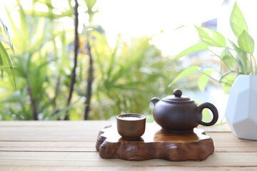 Earthenware tea pot and cup with wooden tray on wooden table
