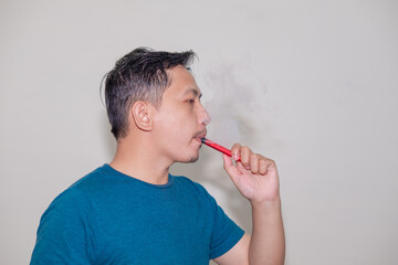 An asian man smoking an e-cigarette or vaporizer.