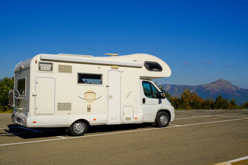 camper van on the road across blue sky and mountains peaks. Adventurous lifestyle. Camper life. Travel in mountains