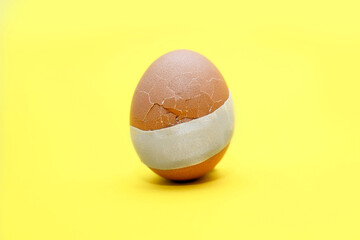 A broken egg with a crack and medical tape glued to it. The concept of treatment and healthcare....