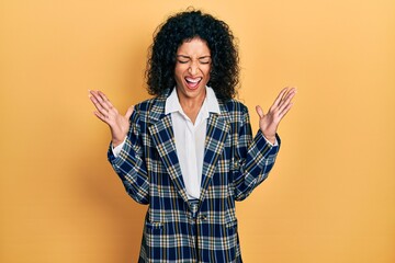Young latin girl wearing business clothes celebrating mad and crazy for success with arms raised...