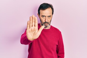 Middle age hispanic man wearing casual clothes doing stop sing with palm of the hand. warning...