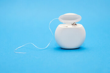 Dental floss for cleaning teeth on a blue background. The concept of oral care and caries...