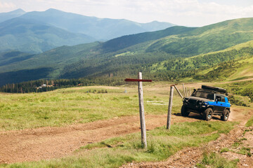 One wooden red signpost in the summer mountain with copyspace. Off-road vehicle goes on the mountain way. Conceptual leading indicator. Old Arrow on the wooden signpost pointing to a direction.