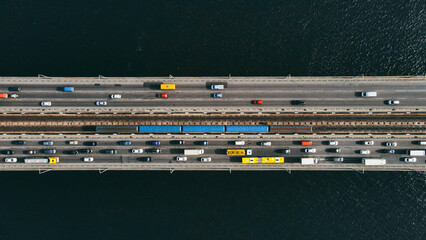 Aerial top view of cars and subway passing the bridge over the river in the city