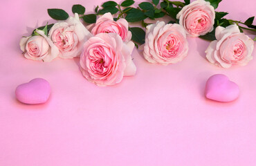 Flowers pink roses with hearts on a pink paper background with space for text. Decoration of Valentine Day