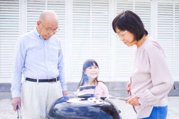 Obraz premium 孫とバーベキューをする高齢の夫婦