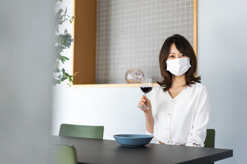 マスクをしてワインを飲む若い女性