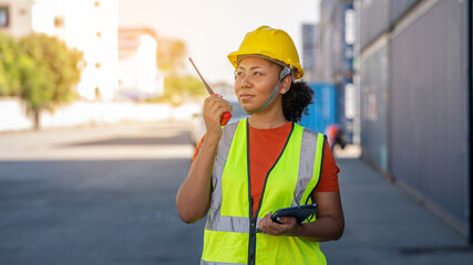 Woman foreman control loading Containers box in warehouse , Worker inspector or Safety Supervisor in Container CustomTerminal port concept import export transportation and logistic service