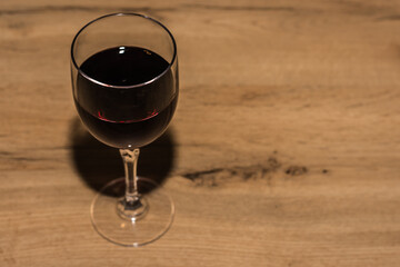 glass of red wine standing on a wooden table close up