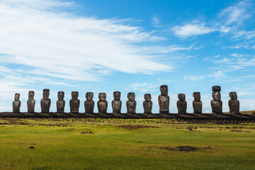 The fifteen moais of the Ahu Tongariki from the front with the green meadow in front and the sunny...