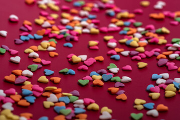 Fototapeta na wymiar Colored heart candies with close-up on a red background