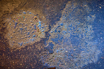 Colorful gas stain on wet asphalt. Oil stain caused by a leak under a car or truck.