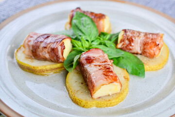 mint rolls with cheese on pear slices in a bowl with basil
