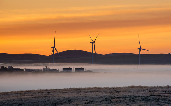 Early morning mist landscape with distant wind farm turbines. 