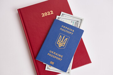 Ukrainian passport and dollar bills on the background of a business diary in 2022
