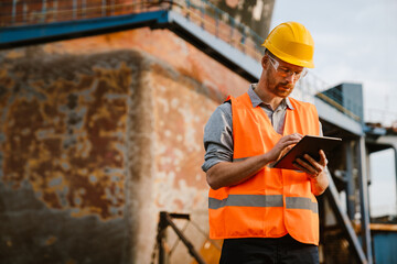 White man wearing helmet using tablet computer while working in port