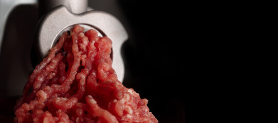 Process of preparing forcemeat by means of a meat grinder. Fresh red mincing close-up on black...
