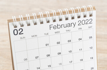 February 2022 desk calendar on wooden background.