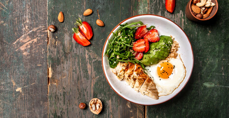 Buddha bowl with chicken, arugula and strawberries. keto diet food recipe background. Long banner format, top view