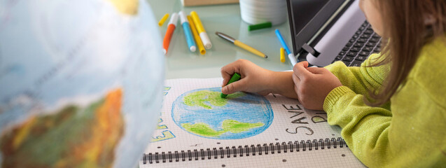Horizontal banner or header with wide angle view of child girl draws planet earth with wax colors...