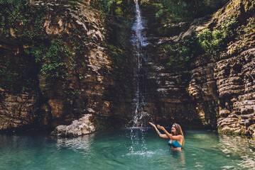 Woman Enjoying Playing with Water of Waterfall