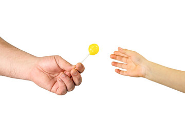 Man give yellow candy lollipop to child boy. Close up man's and kid's hands on white background....