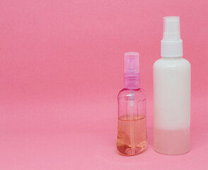 Two spray bottles on a pink background