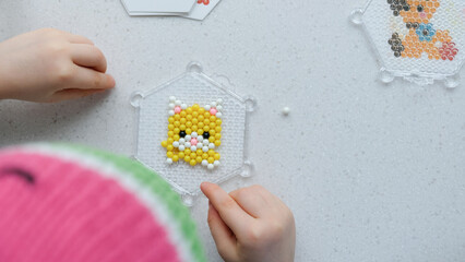 The child lays out an aqua mosaic in the form of a cat's muzzle